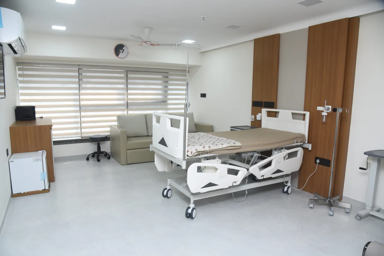 Bright patient room with an adjustable hospital bed and window blinds