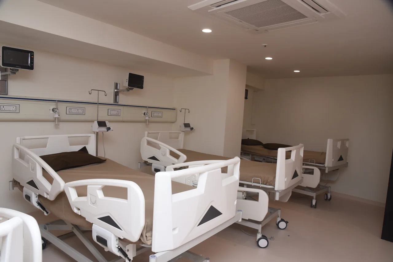 Shared hospital ward with several beds and bedside monitors